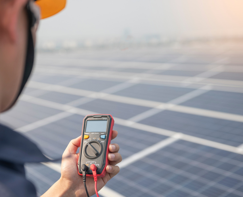 Engineer Holding Tool In Front Of Solar Panels